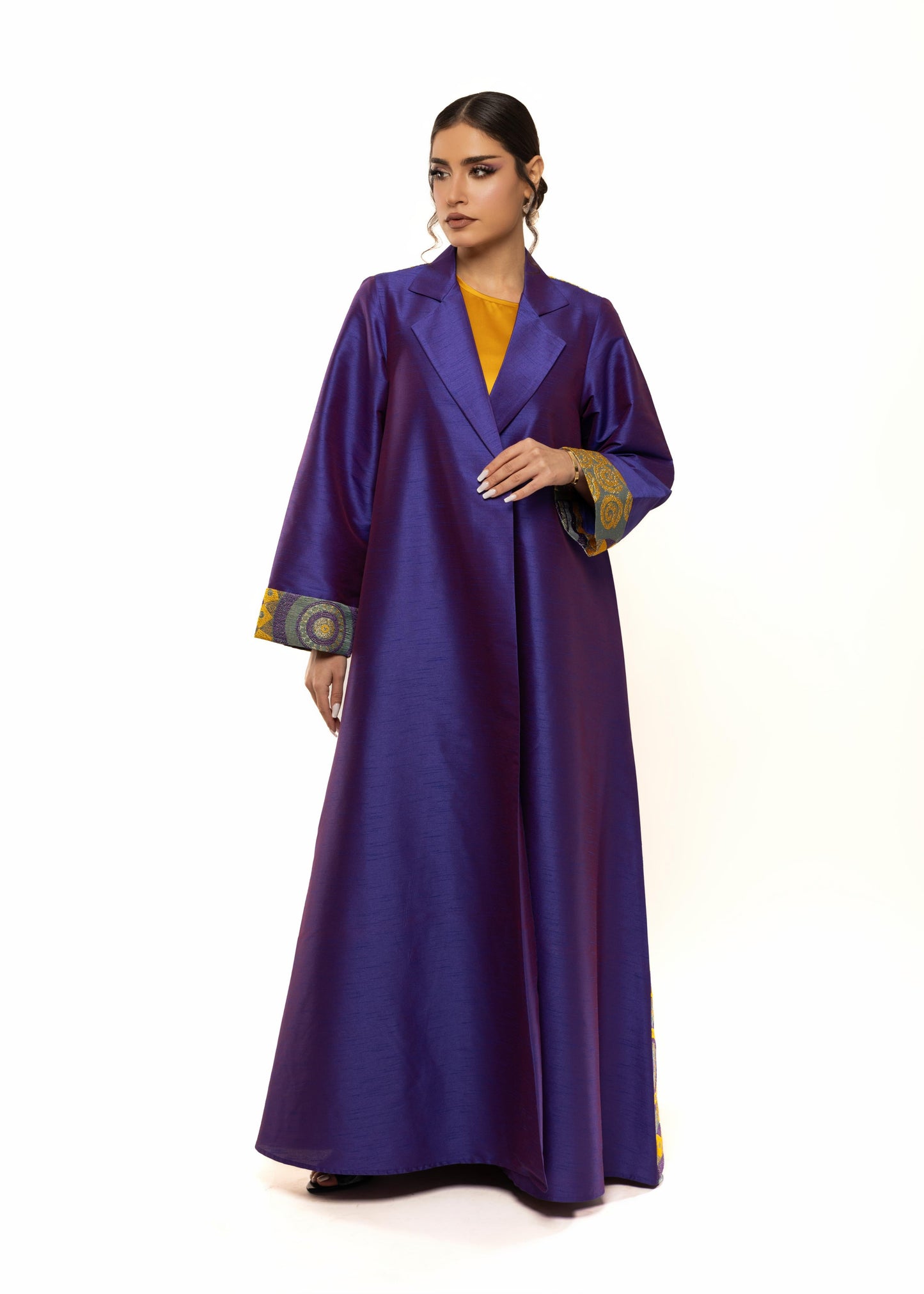 Woman wearing a long purple dress with gold accents on a white background