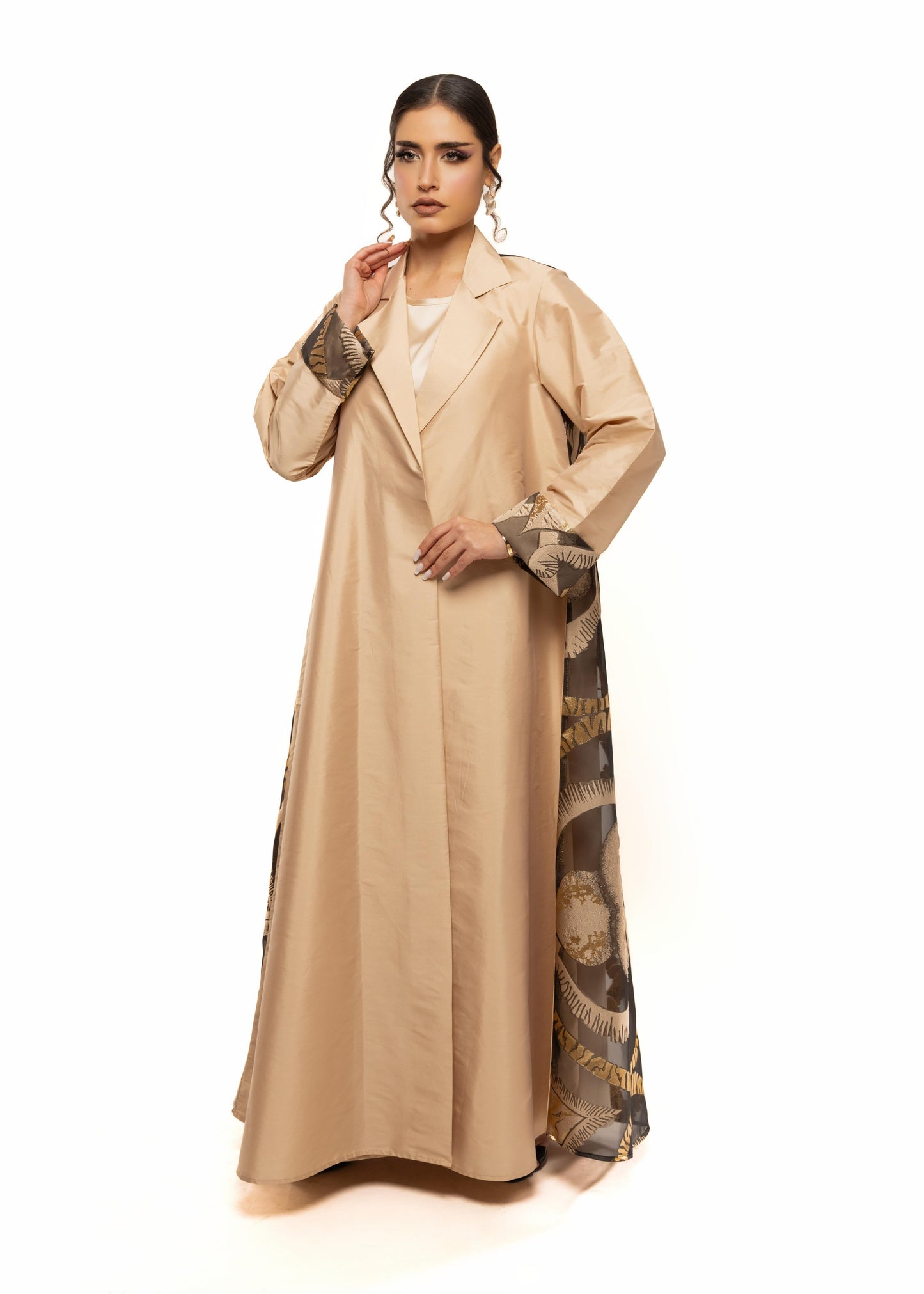 Woman wearing a beige abaya with intricate patterns on a white background