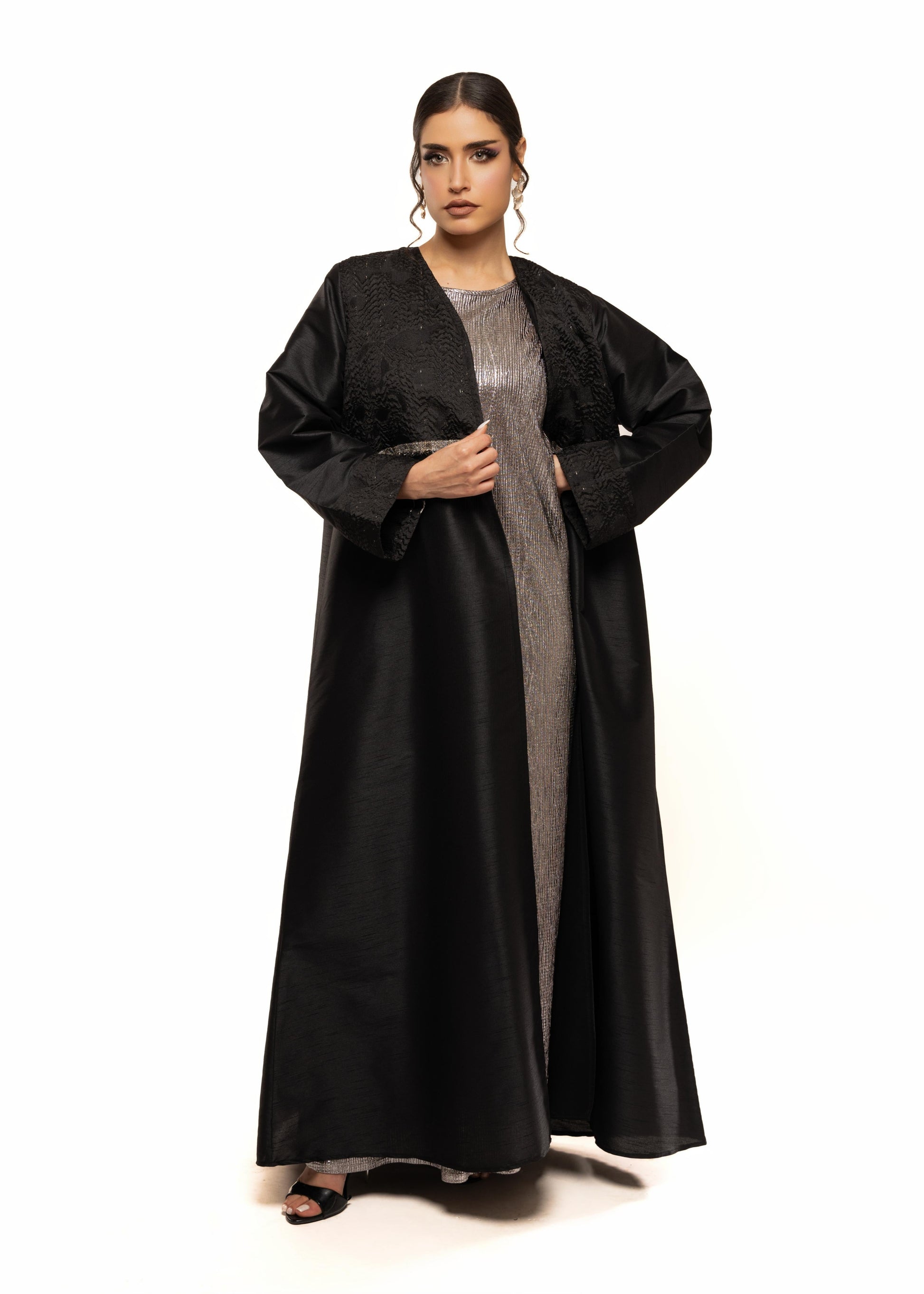 Woman wearing a black abaya with a sheer overlay on a white background