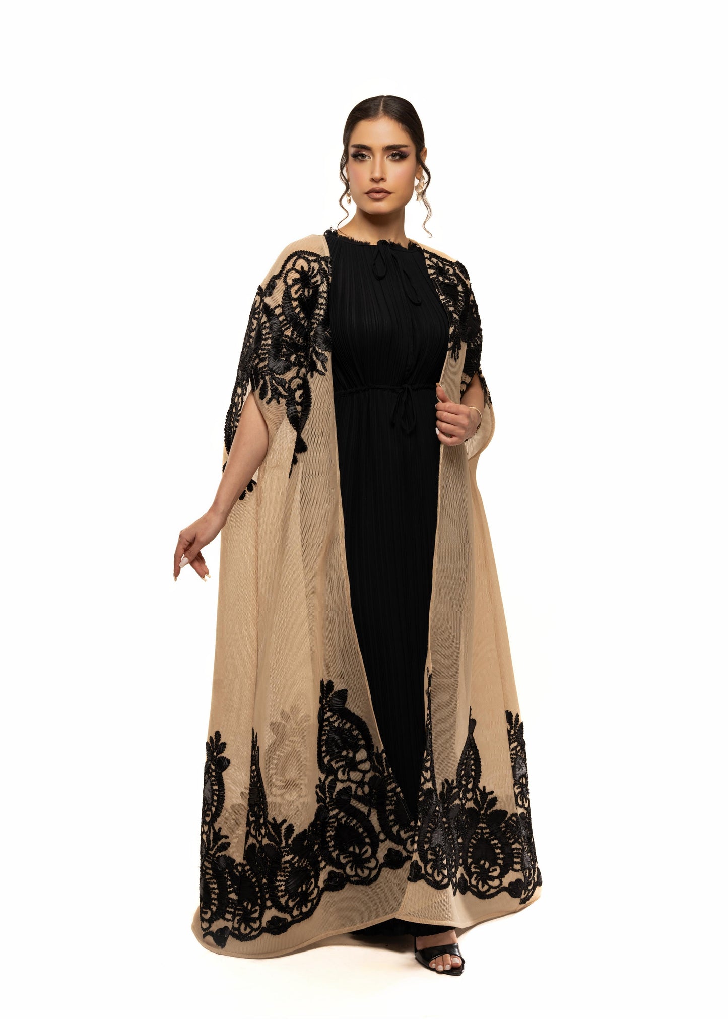Woman wearing a black and beige dress with lace detailing on a white background