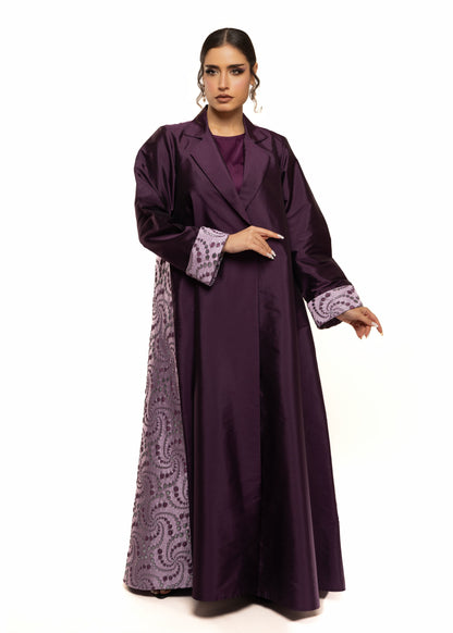 Woman wearing a long purple dress with patterned trim on a white background